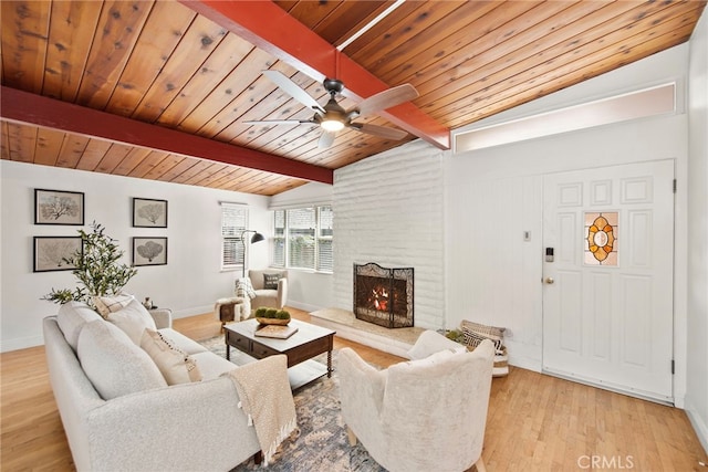 living room featuring wood ceiling, vaulted ceiling with beams, light hardwood / wood-style floors, ceiling fan, and a brick fireplace