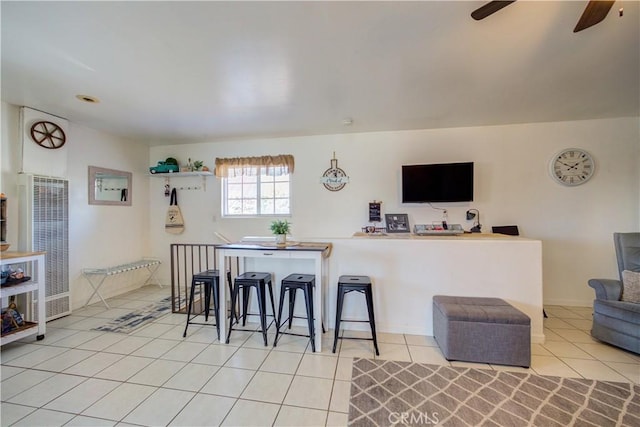 kitchen with a breakfast bar, light tile patterned floors, ceiling fan, and kitchen peninsula