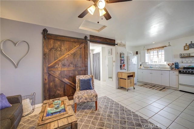 interior space featuring sink, white cabinetry, light tile patterned floors, white appliances, and a barn door