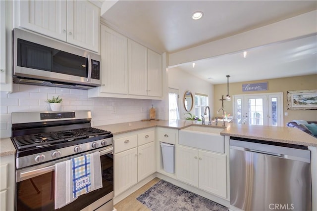 kitchen featuring white cabinetry, sink, hanging light fixtures, kitchen peninsula, and stainless steel appliances