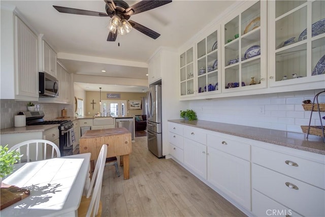 kitchen featuring ceiling fan, white cabinetry, stainless steel appliances, light hardwood / wood-style floors, and decorative light fixtures