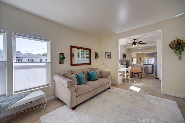 living room with ceiling fan and light hardwood / wood-style flooring