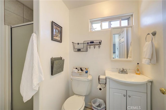 bathroom featuring vanity, a shower with shower door, and toilet