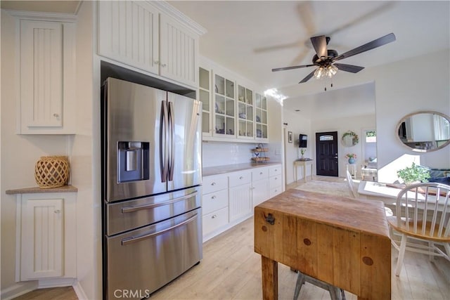 kitchen with white cabinetry, stainless steel fridge, ceiling fan, light hardwood / wood-style floors, and decorative backsplash