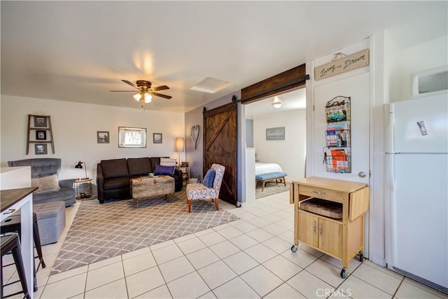 living room featuring light tile patterned floors, a barn door, and ceiling fan