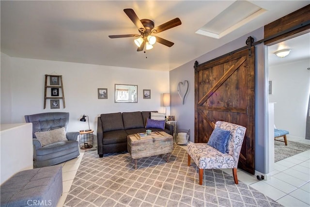 living room featuring light tile patterned flooring, ceiling fan, and a barn door