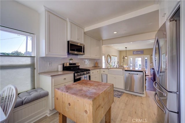 kitchen with stainless steel appliances, white cabinetry, hanging light fixtures, and kitchen peninsula