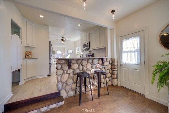 kitchen with tasteful backsplash, stainless steel appliances, kitchen peninsula, and white cabinets