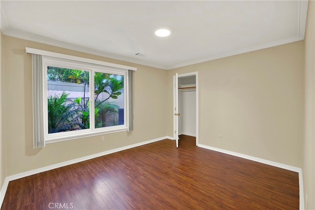 unfurnished bedroom with dark wood-style floors, a closet, ornamental molding, and baseboards