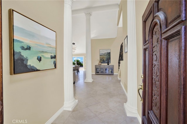 hallway featuring baseboards, light tile patterned flooring, and ornate columns