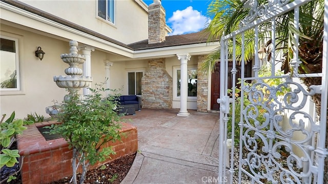 view of exterior entry with stone siding, a chimney, and stucco siding