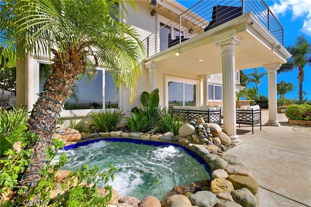 exterior space with an outdoor hangout area, a balcony, and an in ground hot tub