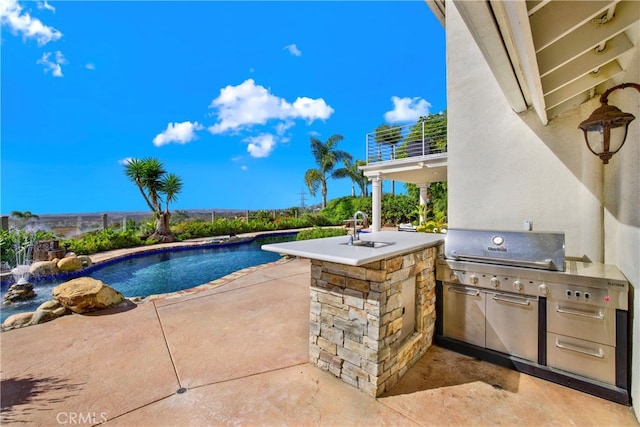 pool with exterior kitchen, a patio area, and a sink