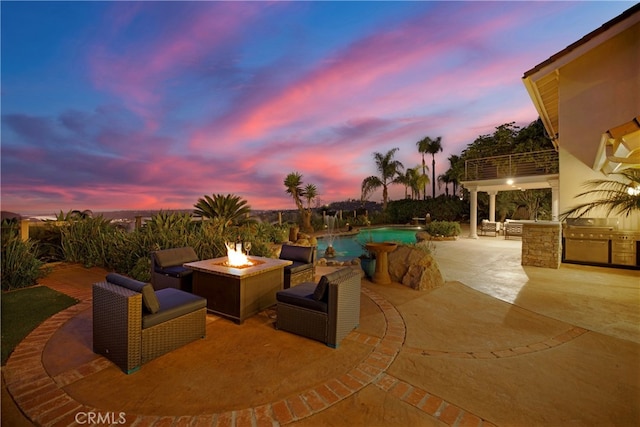 view of patio / terrace with an outdoor pool, a fire pit, and an outdoor kitchen