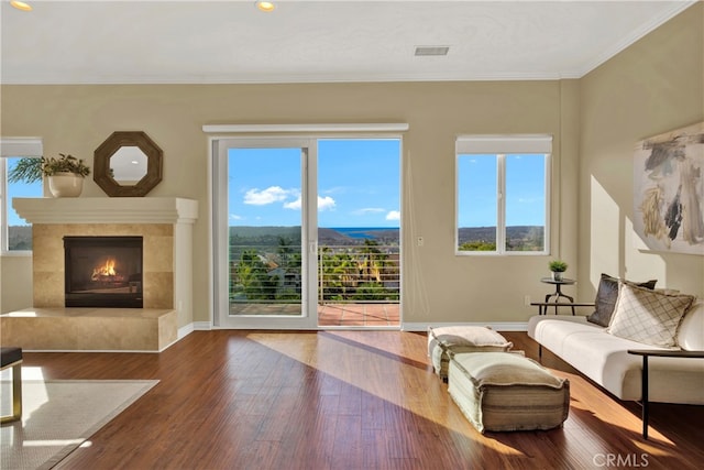 living area featuring visible vents, ornamental molding, a high end fireplace, wood finished floors, and baseboards