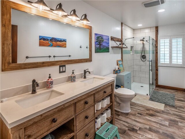 bathroom featuring vanity, toilet, a tile shower, and wood-type flooring