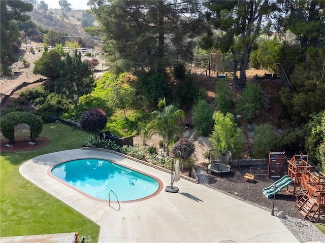 view of swimming pool with a playground, a patio, and a yard