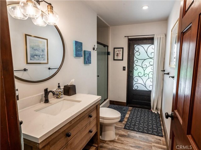 bathroom with hardwood / wood-style flooring, vanity, toilet, and a shower with shower door