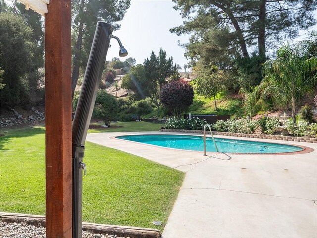 view of swimming pool with a yard and a patio