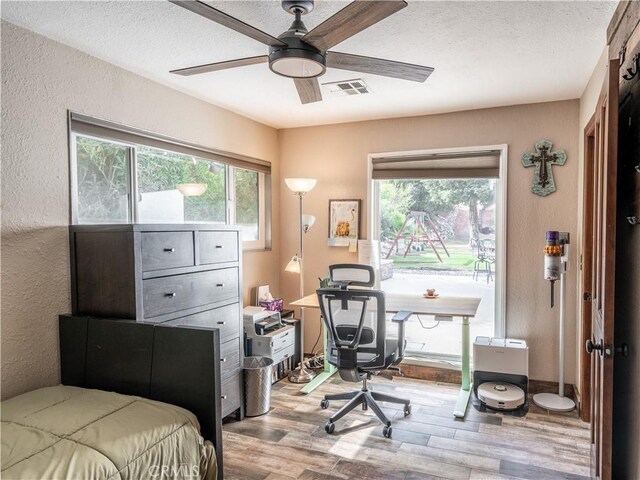 bedroom featuring a textured ceiling, light wood-type flooring, and ceiling fan