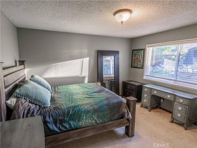 bedroom with a textured ceiling and light colored carpet