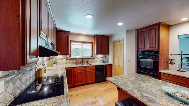 kitchen with light hardwood / wood-style floors, light stone countertops, black appliances, and sink