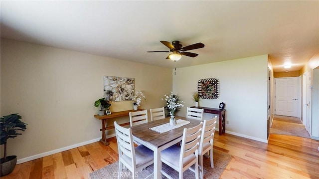 dining space with baseboards, ceiling fan, and light wood-style floors