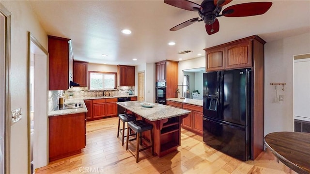 kitchen featuring sink, a breakfast bar area, tasteful backsplash, a kitchen island, and black appliances