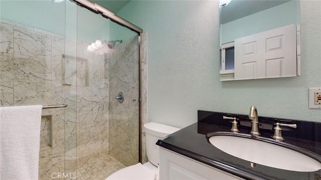 full bath featuring a stall shower, a textured wall, vanity, and toilet