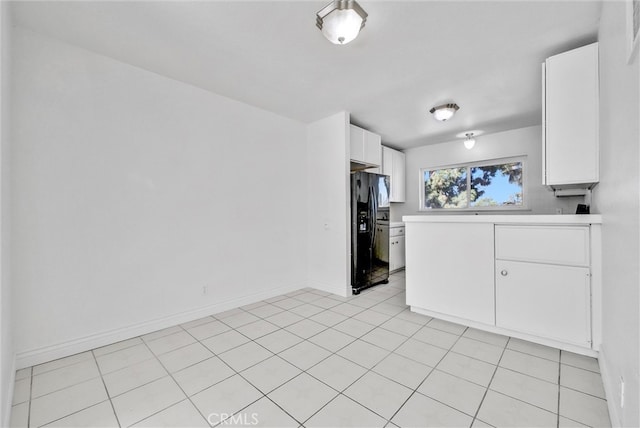 kitchen with black refrigerator with ice dispenser, white cabinetry, and light tile patterned floors