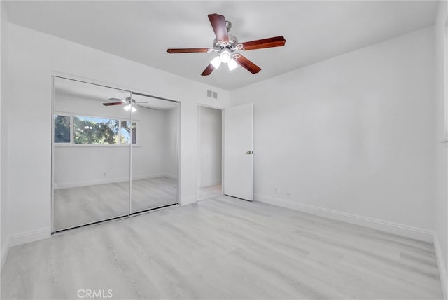 unfurnished bedroom featuring light hardwood / wood-style floors, a closet, and ceiling fan