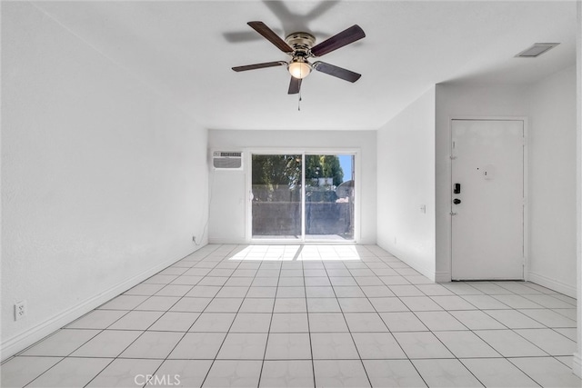 tiled spare room featuring a wall unit AC and ceiling fan