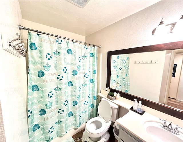 bathroom with a shower with curtain, vanity, a textured ceiling, and toilet