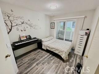 bedroom with access to exterior and dark wood-type flooring