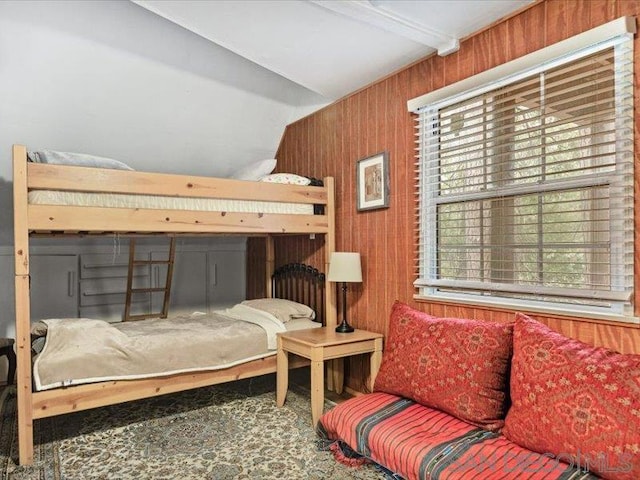 bedroom with wood walls and beamed ceiling