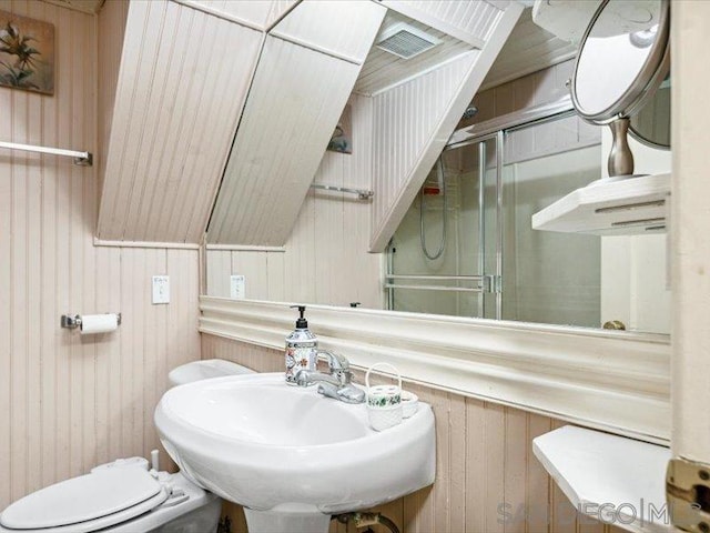 bathroom featuring wood walls, sink, lofted ceiling, and toilet