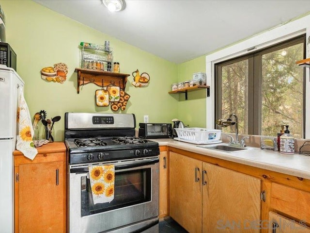 kitchen with vaulted ceiling, stainless steel gas range oven, and sink