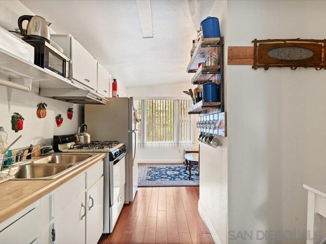 kitchen with gas range gas stove, sink, dark wood-type flooring, vaulted ceiling, and white cabinets