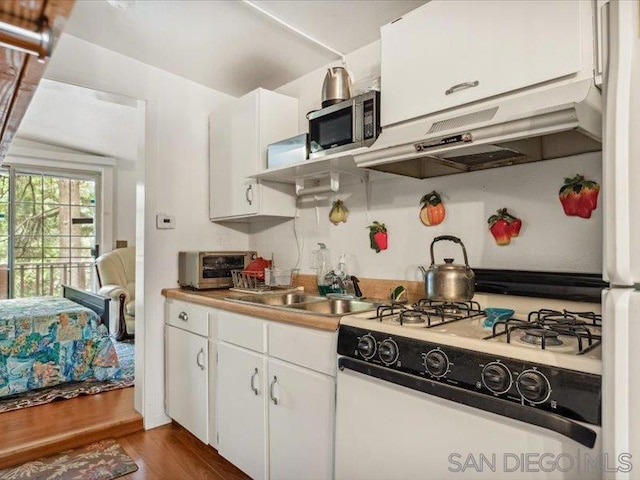 kitchen featuring white cabinets, white gas stove, dark hardwood / wood-style floors, and sink