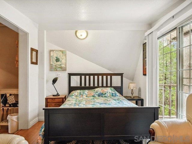 bedroom featuring light hardwood / wood-style floors and vaulted ceiling