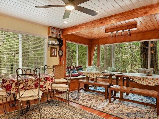 sunroom / solarium featuring ceiling fan, beamed ceiling, and wood ceiling