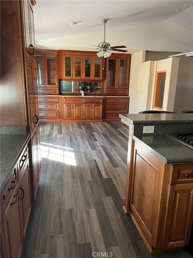 kitchen featuring dark wood-type flooring, vaulted ceiling, stainless steel stovetop, and ceiling fan