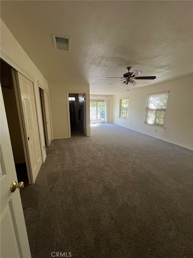 carpeted empty room with ceiling fan and a textured ceiling