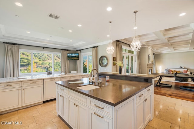 kitchen featuring decorative light fixtures, a center island with sink, sink, coffered ceiling, and light tile patterned floors