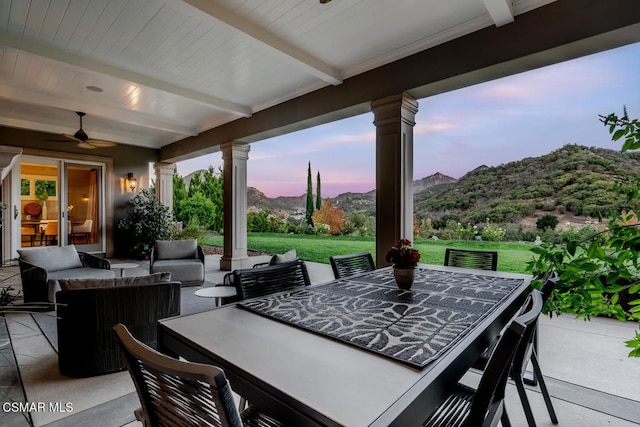 patio terrace at dusk with a mountain view, outdoor lounge area, a lawn, and ceiling fan