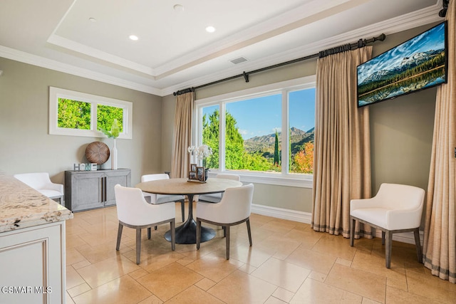 dining room with a raised ceiling, a wealth of natural light, and crown molding