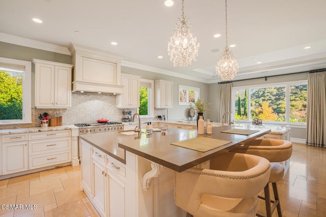 kitchen with hanging light fixtures, a breakfast bar, sink, and an island with sink