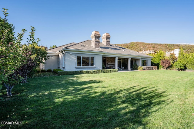 back of house with a patio area and a lawn