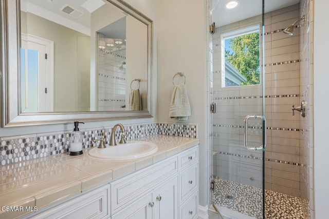 bathroom featuring decorative backsplash, a shower with shower door, and vanity