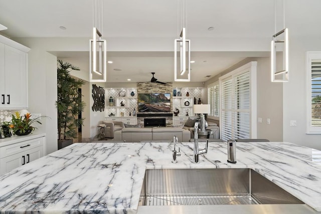 kitchen featuring white cabinets, decorative light fixtures, and light stone counters